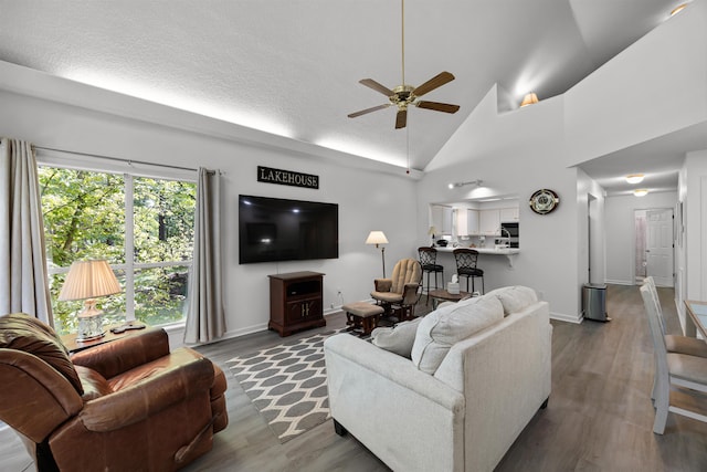 living room featuring dark hardwood / wood-style flooring, high vaulted ceiling, ceiling fan, and a textured ceiling