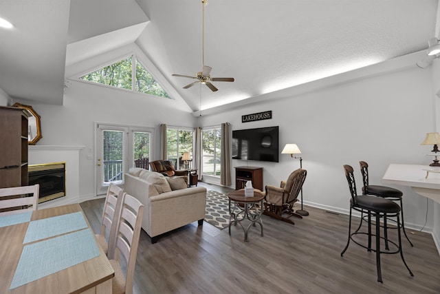 living room with plenty of natural light, ceiling fan, dark hardwood / wood-style floors, and high vaulted ceiling