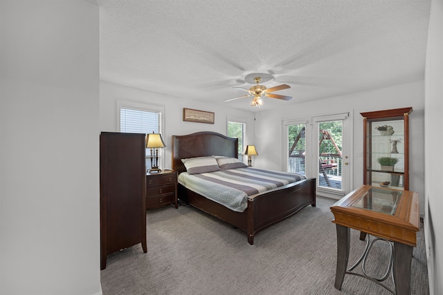 bedroom with a textured ceiling, light colored carpet, ceiling fan, and access to outside