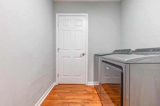 laundry room with washing machine and clothes dryer and light hardwood / wood-style floors