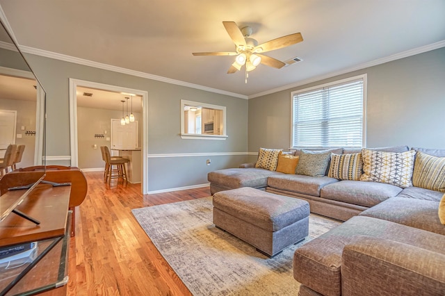 living room featuring ceiling fan with notable chandelier, hardwood / wood-style flooring, and ornamental molding