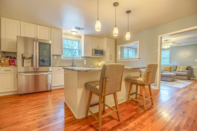 kitchen with light hardwood / wood-style flooring, light stone countertops, stainless steel appliances, ceiling fan, and a breakfast bar