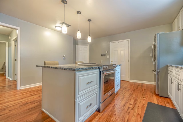 kitchen featuring white cabinetry, light hardwood / wood-style flooring, decorative light fixtures, a kitchen island, and appliances with stainless steel finishes