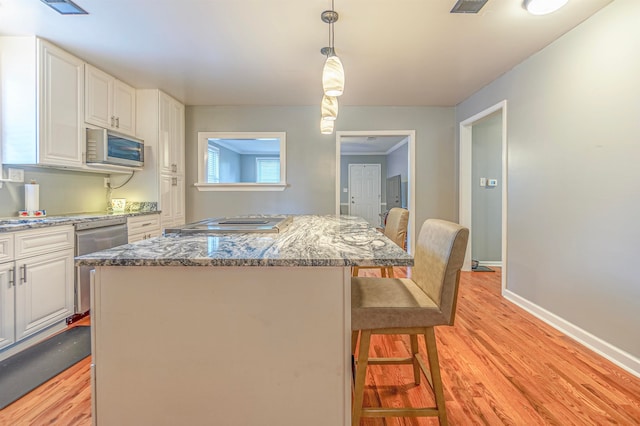 kitchen featuring a center island, appliances with stainless steel finishes, a kitchen breakfast bar, and light hardwood / wood-style floors