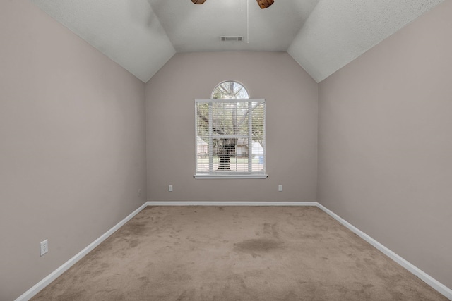 empty room with light carpet, vaulted ceiling, ceiling fan, and a textured ceiling