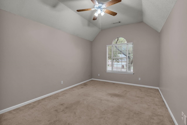 carpeted empty room with a textured ceiling, vaulted ceiling, and ceiling fan