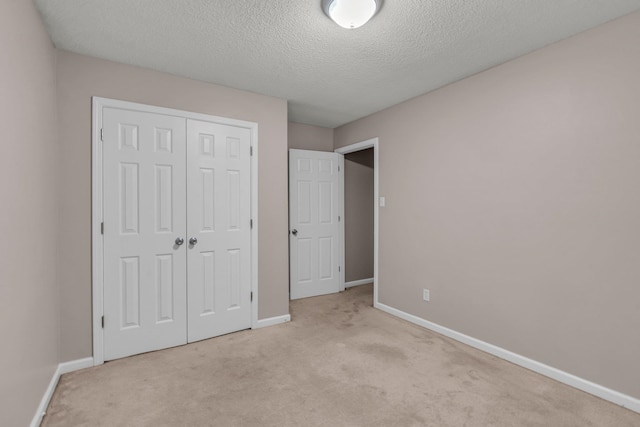 unfurnished bedroom featuring light carpet, a closet, and a textured ceiling