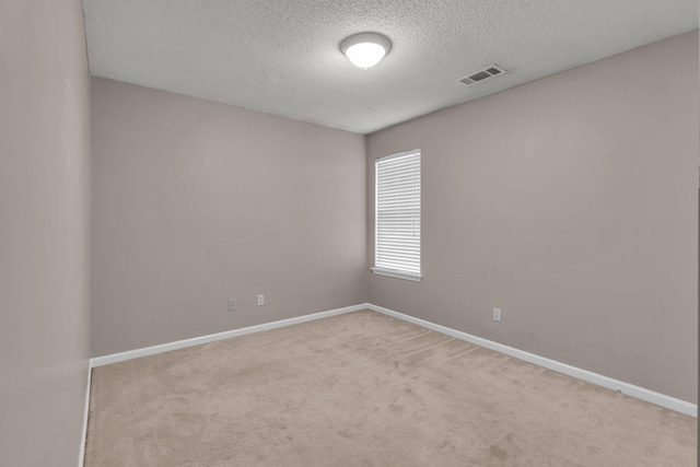 empty room featuring a textured ceiling and light colored carpet