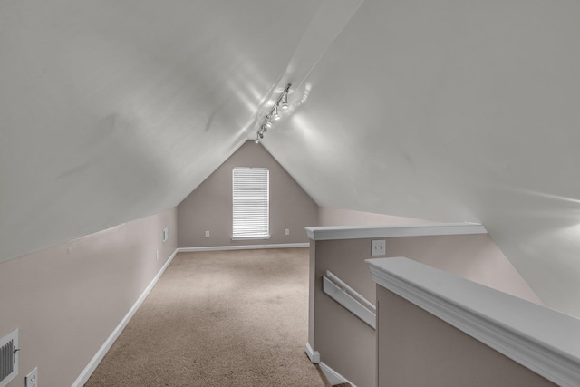 additional living space with light colored carpet and vaulted ceiling