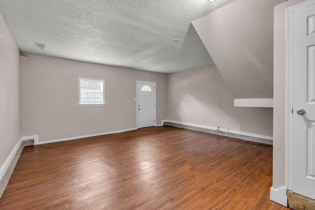 additional living space featuring a textured ceiling and hardwood / wood-style floors