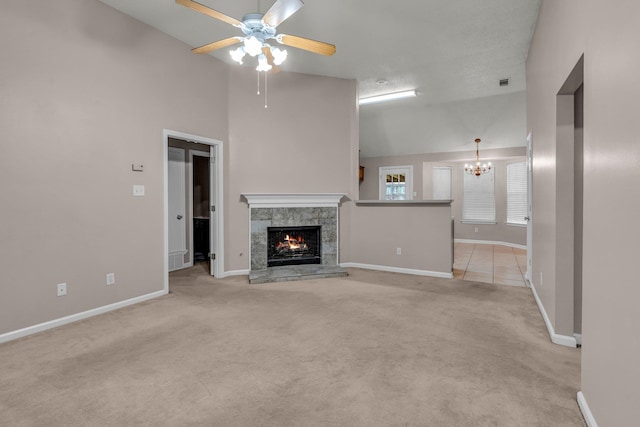 unfurnished living room with ceiling fan with notable chandelier, a premium fireplace, high vaulted ceiling, and light carpet