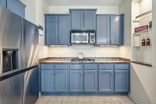 kitchen with stainless steel appliances, blue cabinets, and light tile patterned floors