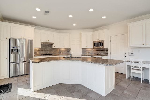 kitchen featuring appliances with stainless steel finishes, a center island with sink, white cabinetry, and tasteful backsplash