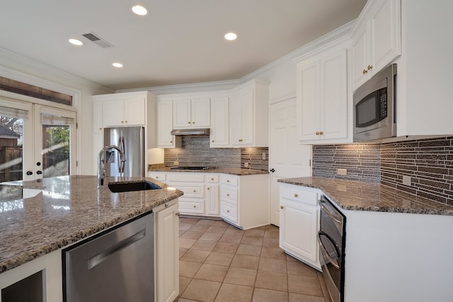 kitchen featuring white cabinets, dark stone countertops, appliances with stainless steel finishes, and sink