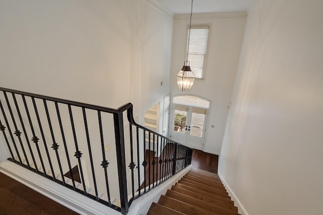 stairs with an inviting chandelier, ornamental molding, and hardwood / wood-style floors