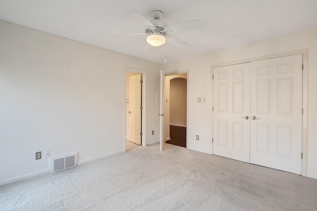 unfurnished bedroom with ceiling fan, light colored carpet, and a closet