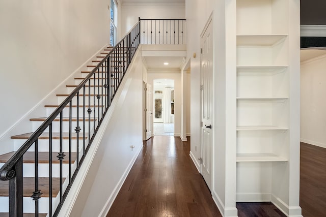 staircase with crown molding, built in shelves, and hardwood / wood-style flooring