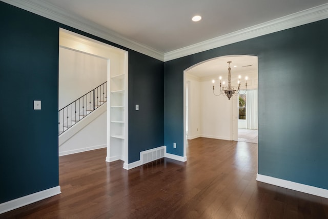 spare room with ornamental molding, dark hardwood / wood-style floors, and an inviting chandelier