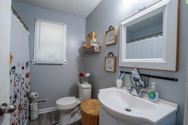 bathroom with vanity, a textured ceiling, hardwood / wood-style floors, and toilet