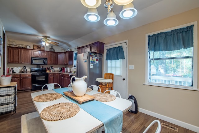 dining space with vaulted ceiling, ceiling fan with notable chandelier, dark wood-type flooring, and a wealth of natural light