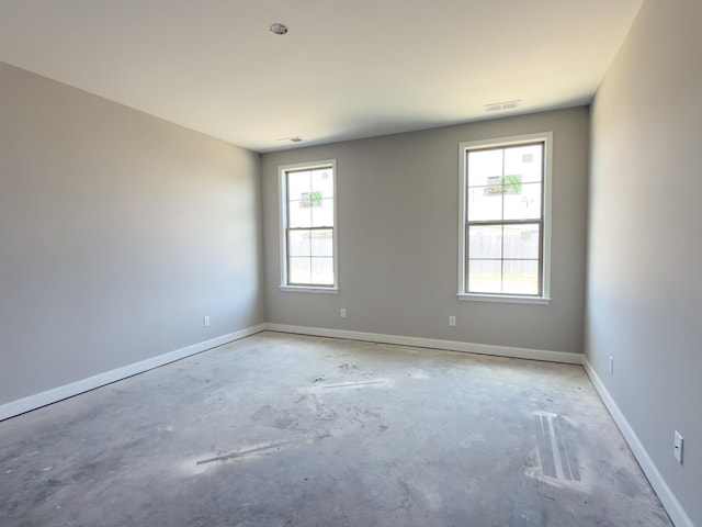 unfurnished room featuring baseboards, concrete floors, and visible vents