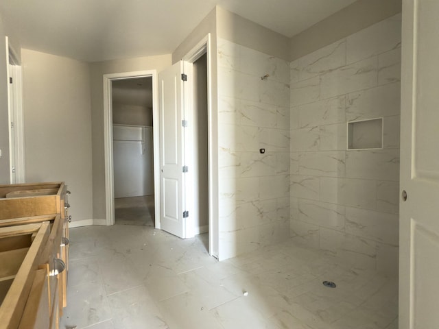 full bath with marble finish floor, vanity, baseboards, and walk in shower