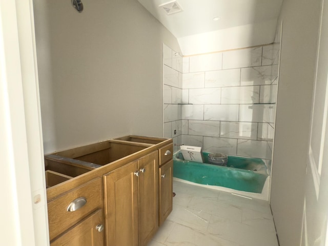 bathroom with marble finish floor, visible vents, and tiled shower