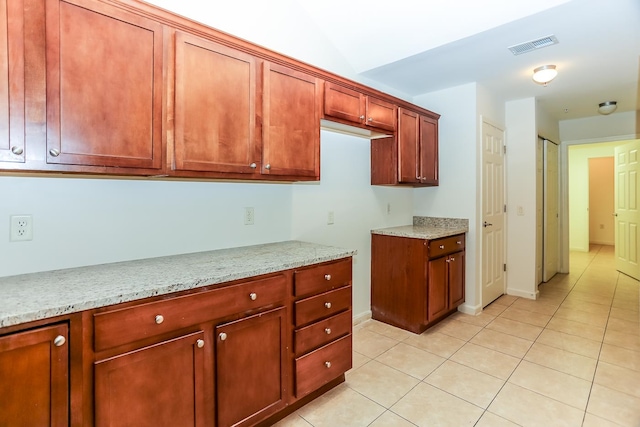 kitchen with light tile patterned floors and light stone counters