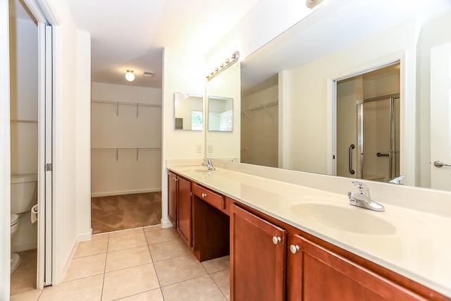 bathroom with tile patterned flooring, a shower with door, toilet, and vanity