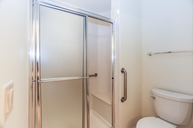 bathroom with a shower with shower door and toilet