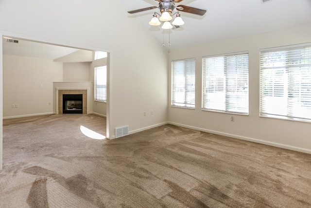 unfurnished living room with ceiling fan, a tile fireplace, carpet flooring, and a healthy amount of sunlight