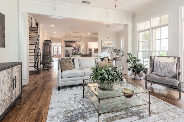 living room with ornamental molding, a chandelier, and dark wood-type flooring