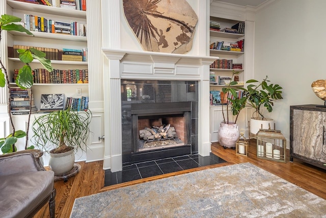 living room featuring ornamental molding, a tile fireplace, dark hardwood / wood-style floors, and built in features