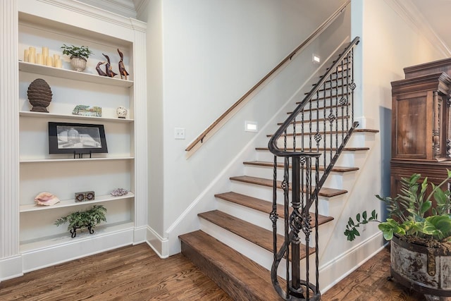 staircase featuring crown molding, built in shelves, and hardwood / wood-style floors