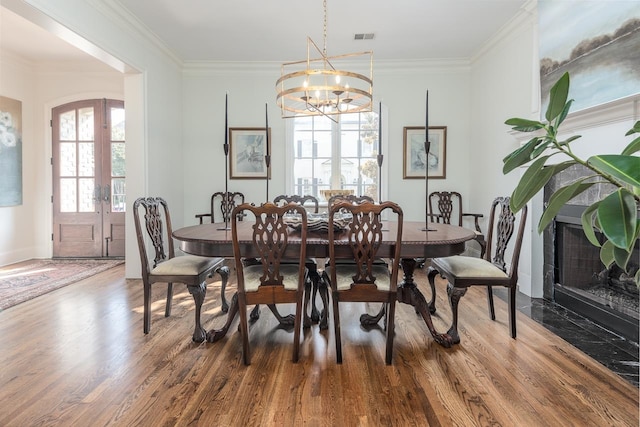 dining area with ornamental molding, an inviting chandelier, french doors, and dark hardwood / wood-style flooring