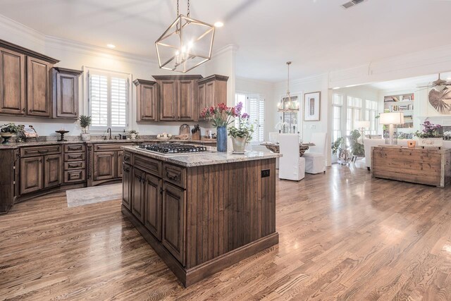 1911 Hazelton Dr, Germantown, TN 38138 - kitchen with dark brown cabinets, crown molding, light stone counters, light wood-style flooring, and stainless steel gas stovetop