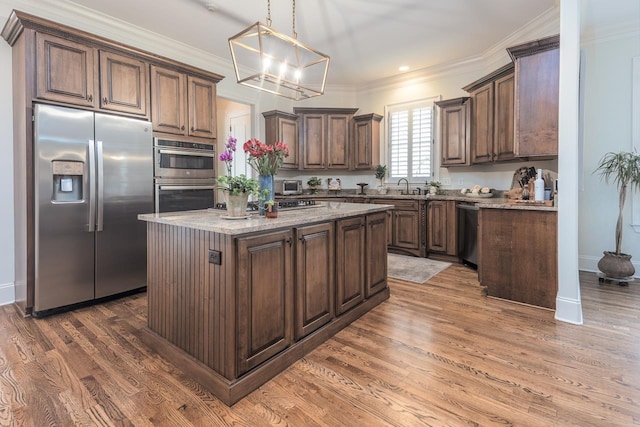 1911 Hazelton Dr, Germantown, TN 38138 - kitchen featuring a center island, ornamental molding, appliances with stainless steel finishes, an inviting chandelier, and wood finished floors