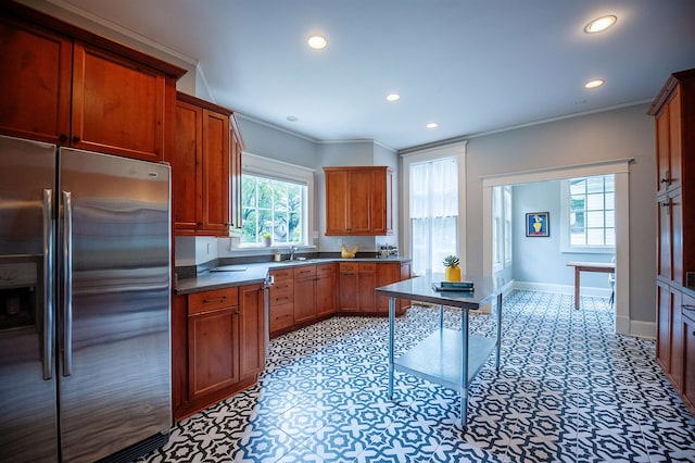 kitchen with sink, plenty of natural light, crown molding, and stainless steel fridge