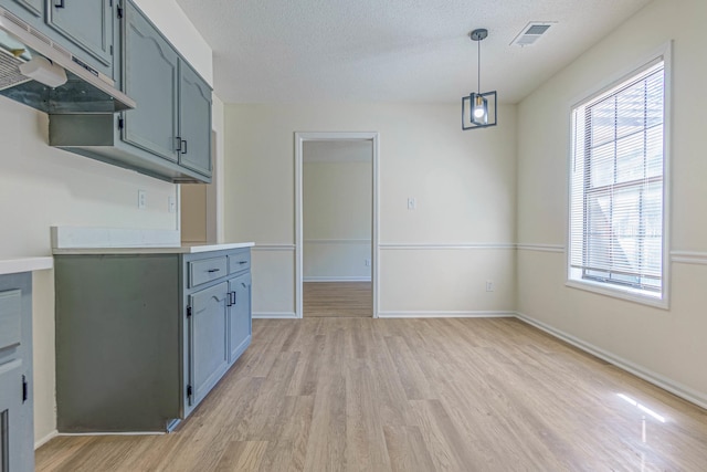 kitchen featuring a wealth of natural light, light hardwood / wood-style floors, decorative light fixtures, and a textured ceiling