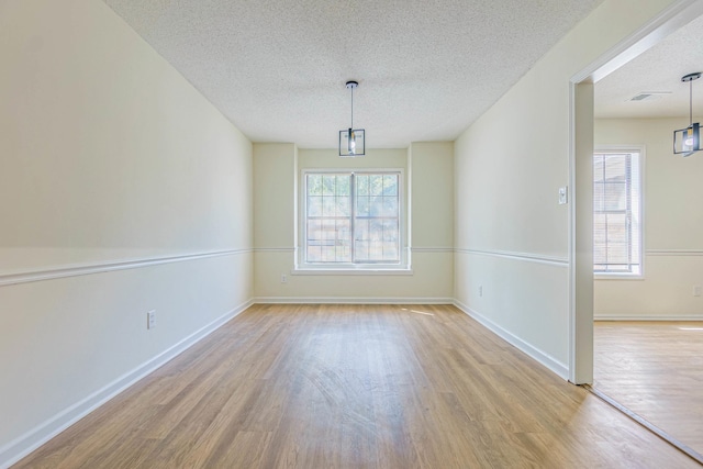 unfurnished room with a textured ceiling and light hardwood / wood-style floors