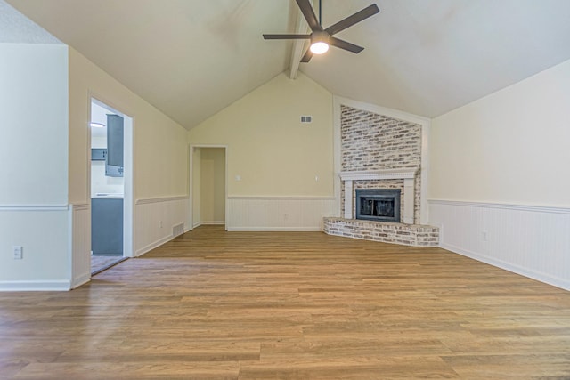 unfurnished living room featuring lofted ceiling with beams, light wood-type flooring, ceiling fan, and a fireplace