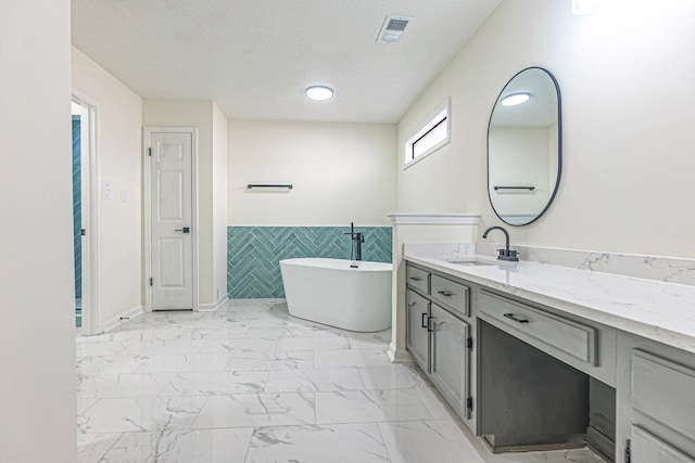 bathroom featuring vanity, tile walls, a textured ceiling, and a bath