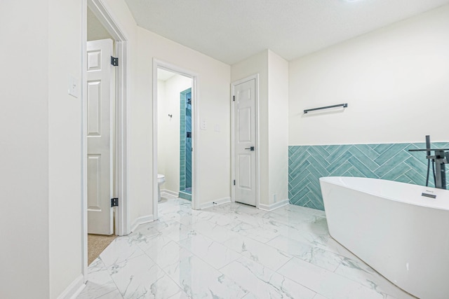 bathroom with a textured ceiling, tile walls, toilet, and a bath