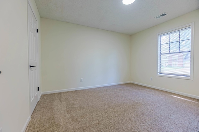 carpeted empty room featuring a textured ceiling