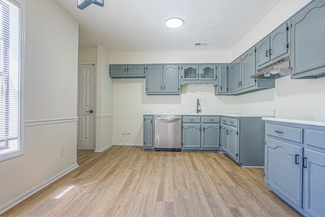 kitchen with a textured ceiling, light hardwood / wood-style floors, sink, and stainless steel dishwasher