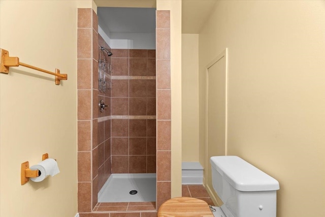 bathroom with tile patterned floors, toilet, and tiled shower