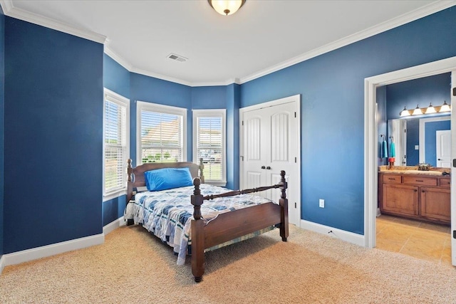 carpeted bedroom featuring ornamental molding, ensuite bathroom, and a closet