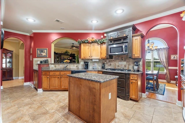 kitchen featuring appliances with stainless steel finishes, crown molding, a center island, and ceiling fan