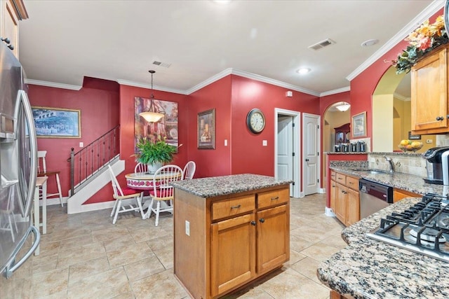 kitchen with decorative light fixtures, stainless steel appliances, crown molding, and a center island