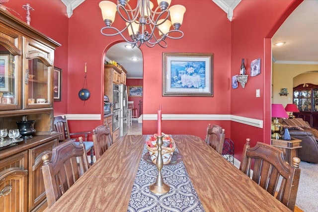 carpeted dining room with a chandelier and crown molding